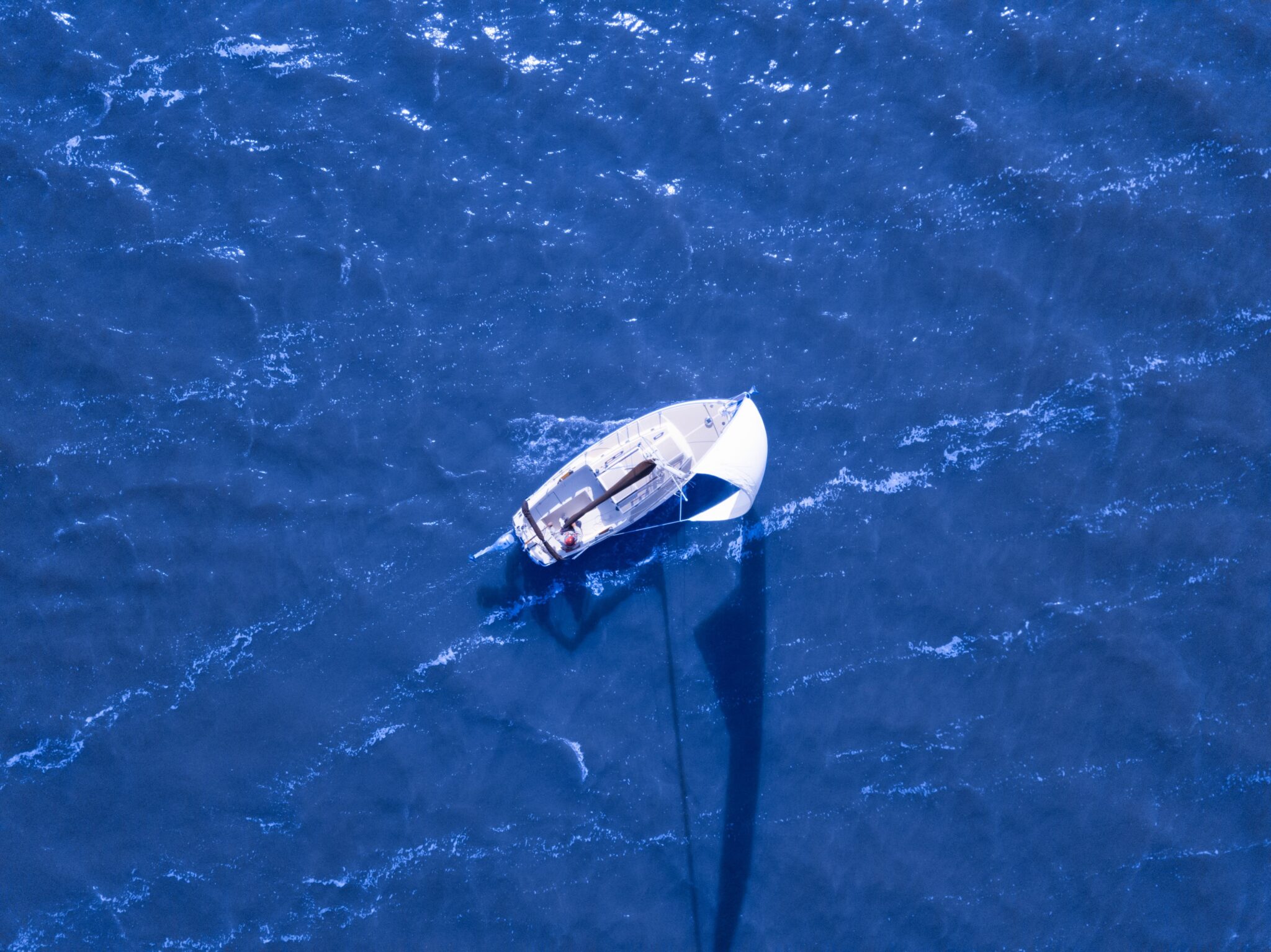 Monohull sailboat in deep blue water from overhead